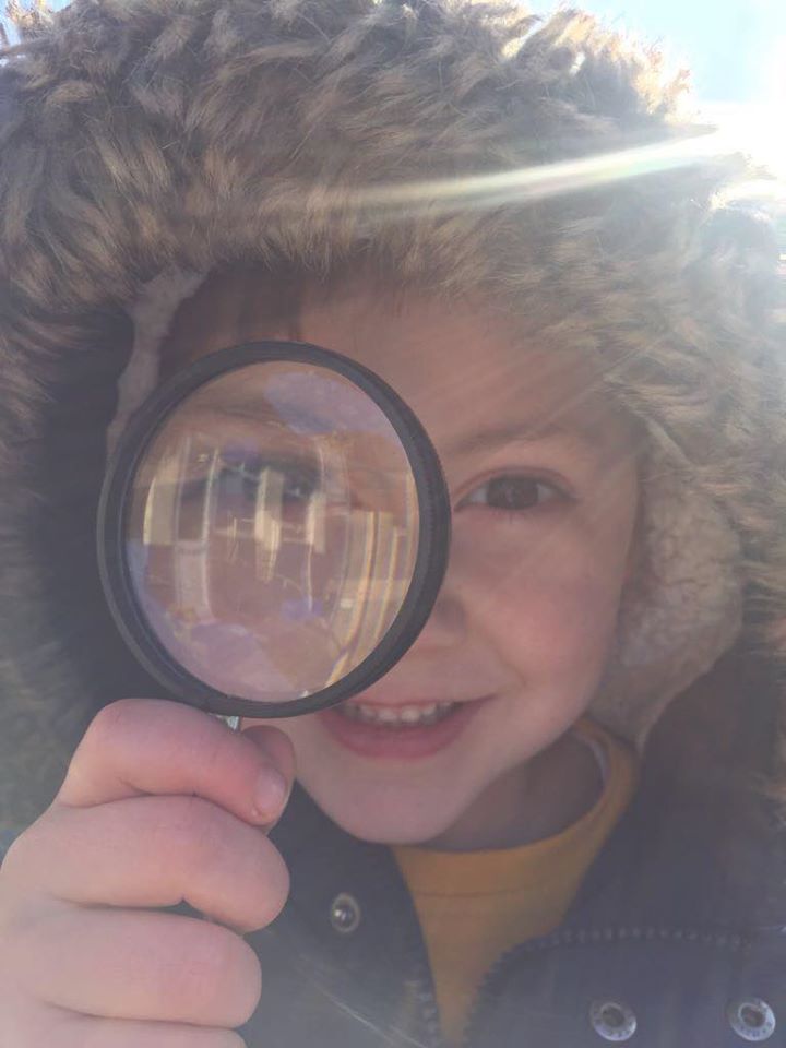 little boy looking through a magnifying glass